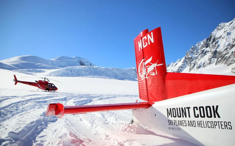 A red Mount Cook ski plane parked on a high snowfield